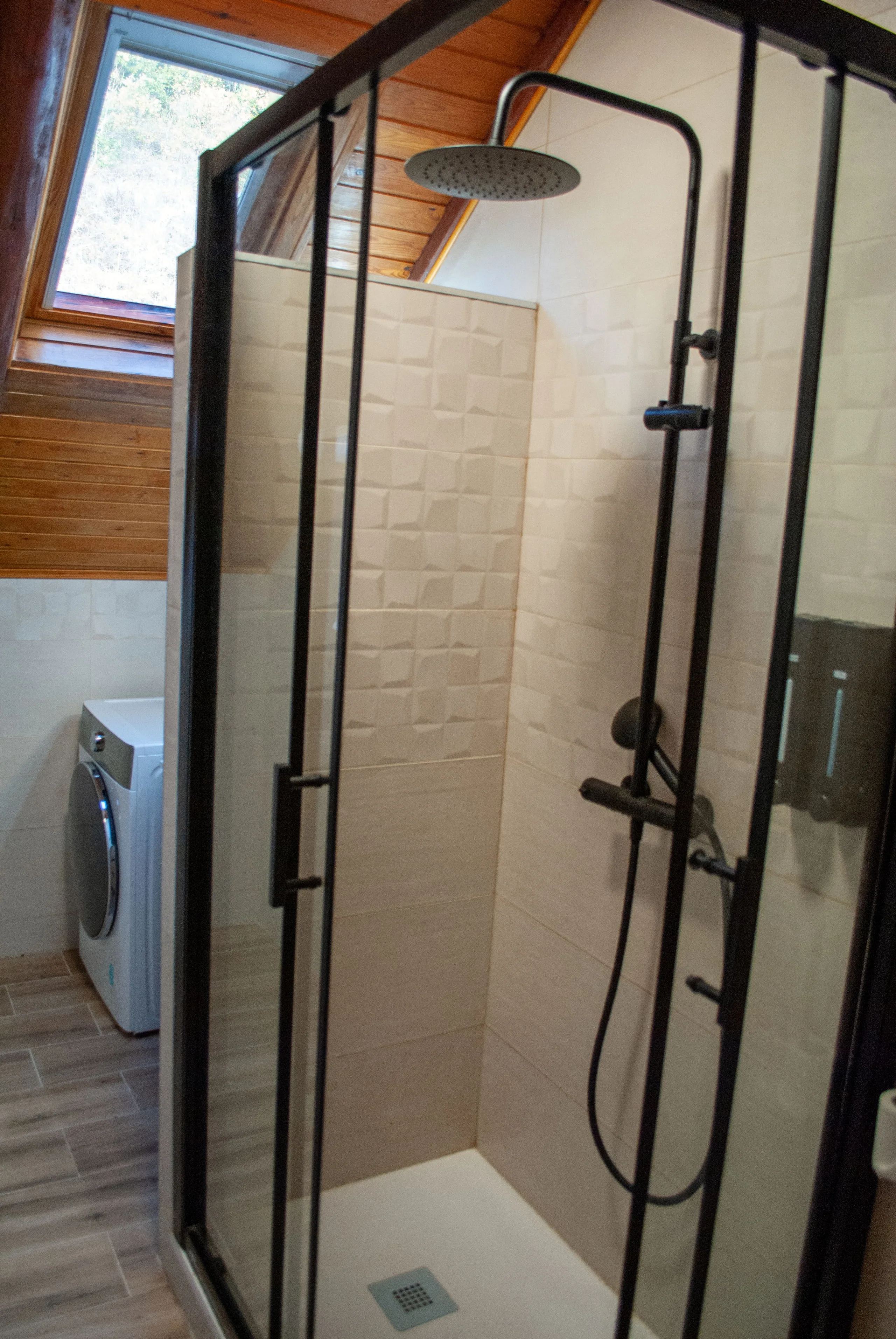 Baño con cabina de ducha acristalada y lavadora