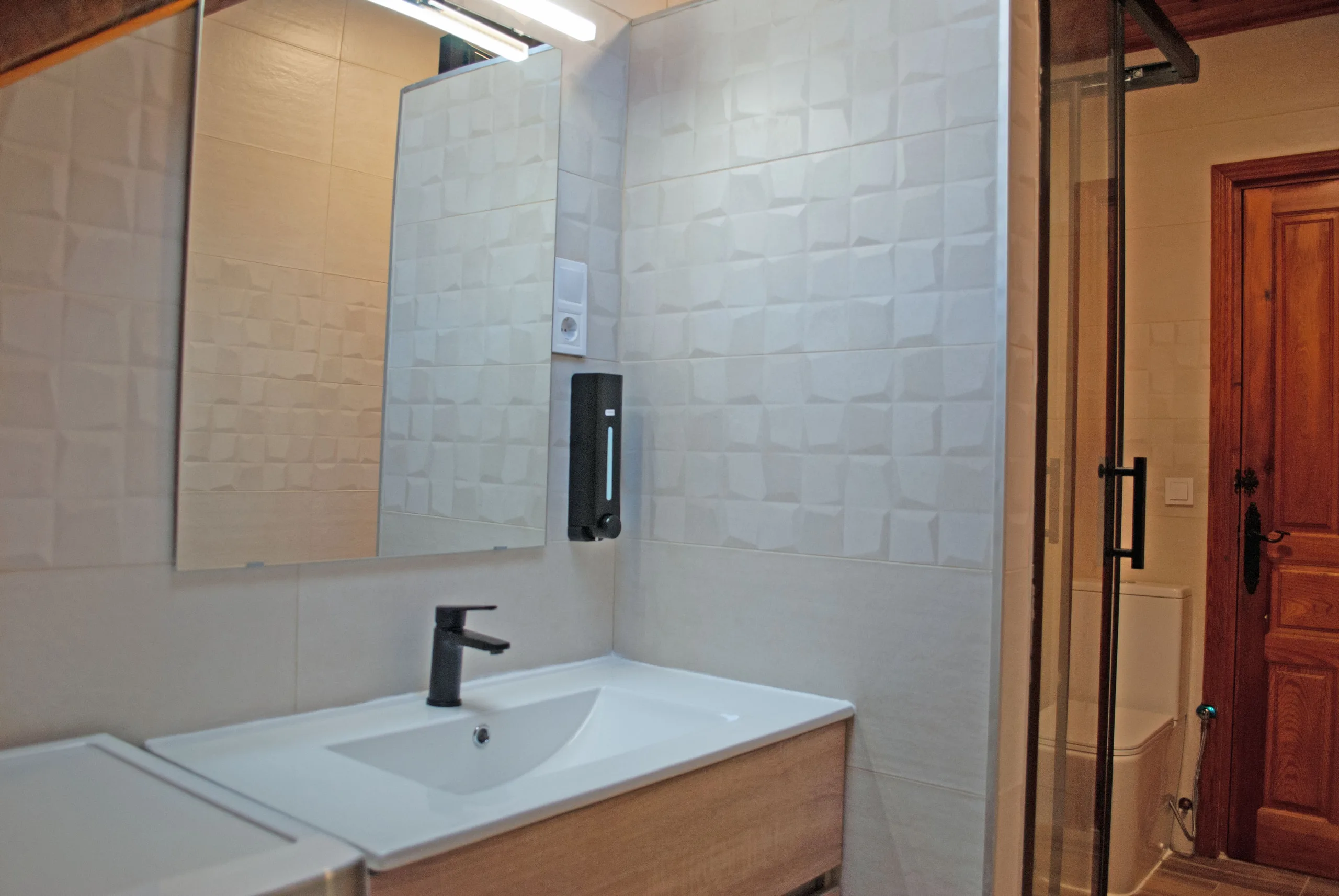 Baño con lavabo, espejo grande y mampara de ducha
