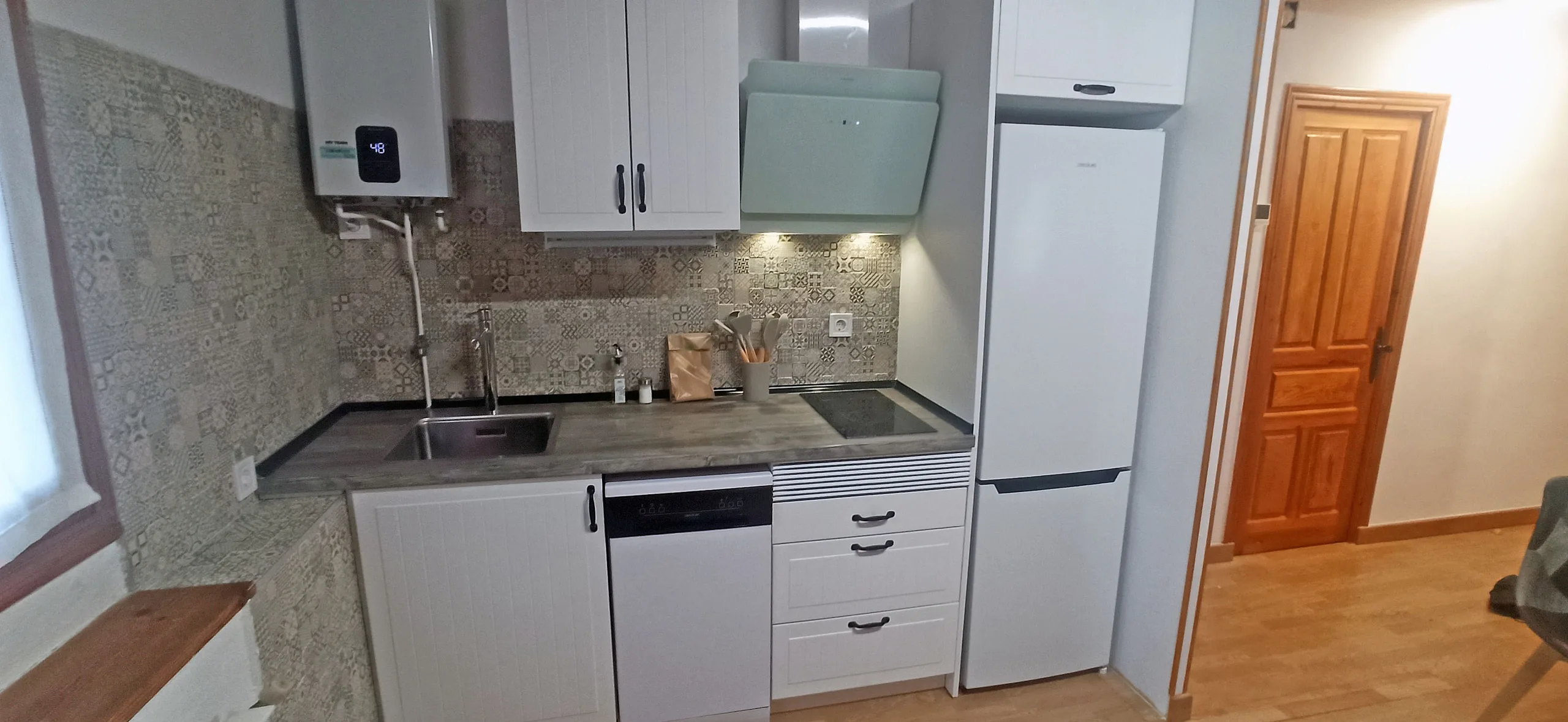 Cocina con muebles blancos, vitrocerámica, fregadero y frigorífico