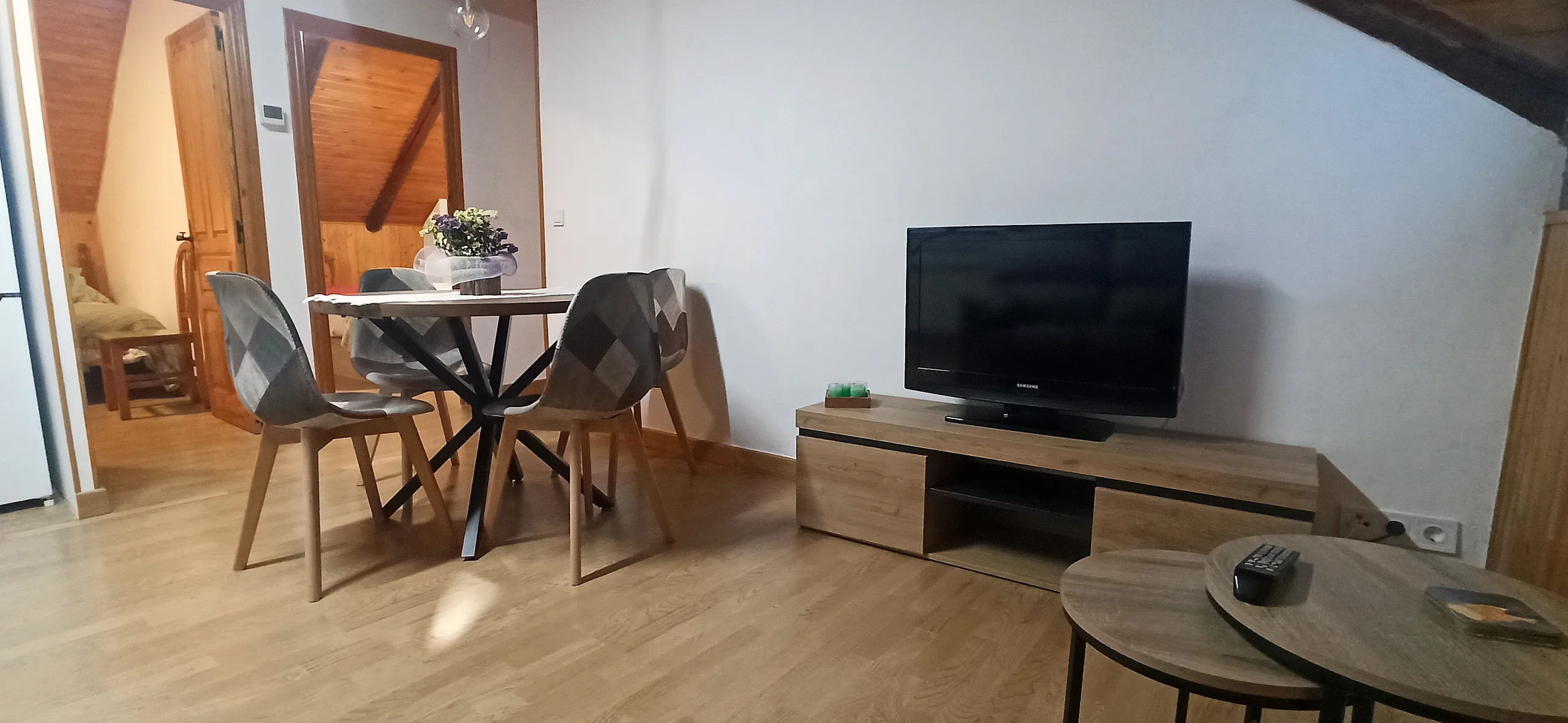 Mesa de comedor con sillas y mueble de televisión, bajo la buhardilla